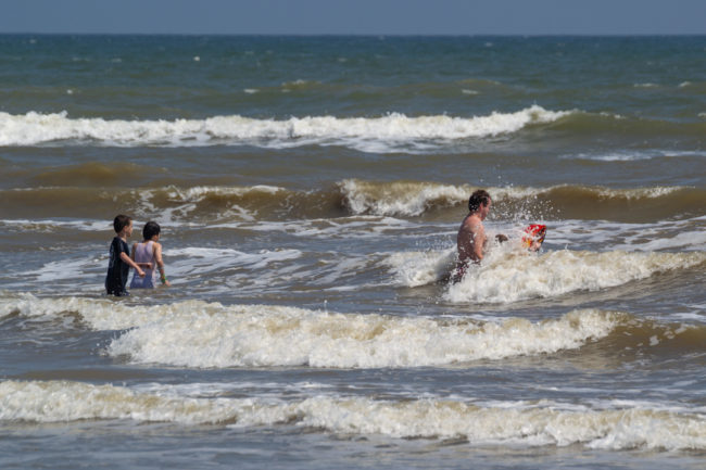 Galveston Island - děti si hrajou ve vlnách oceánu
