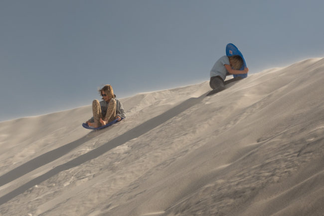 Děti bobujou na písečných dunách - White Sands